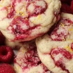 Lemon Raspberry Cookies on a plate with a fresh lemon and raspberries